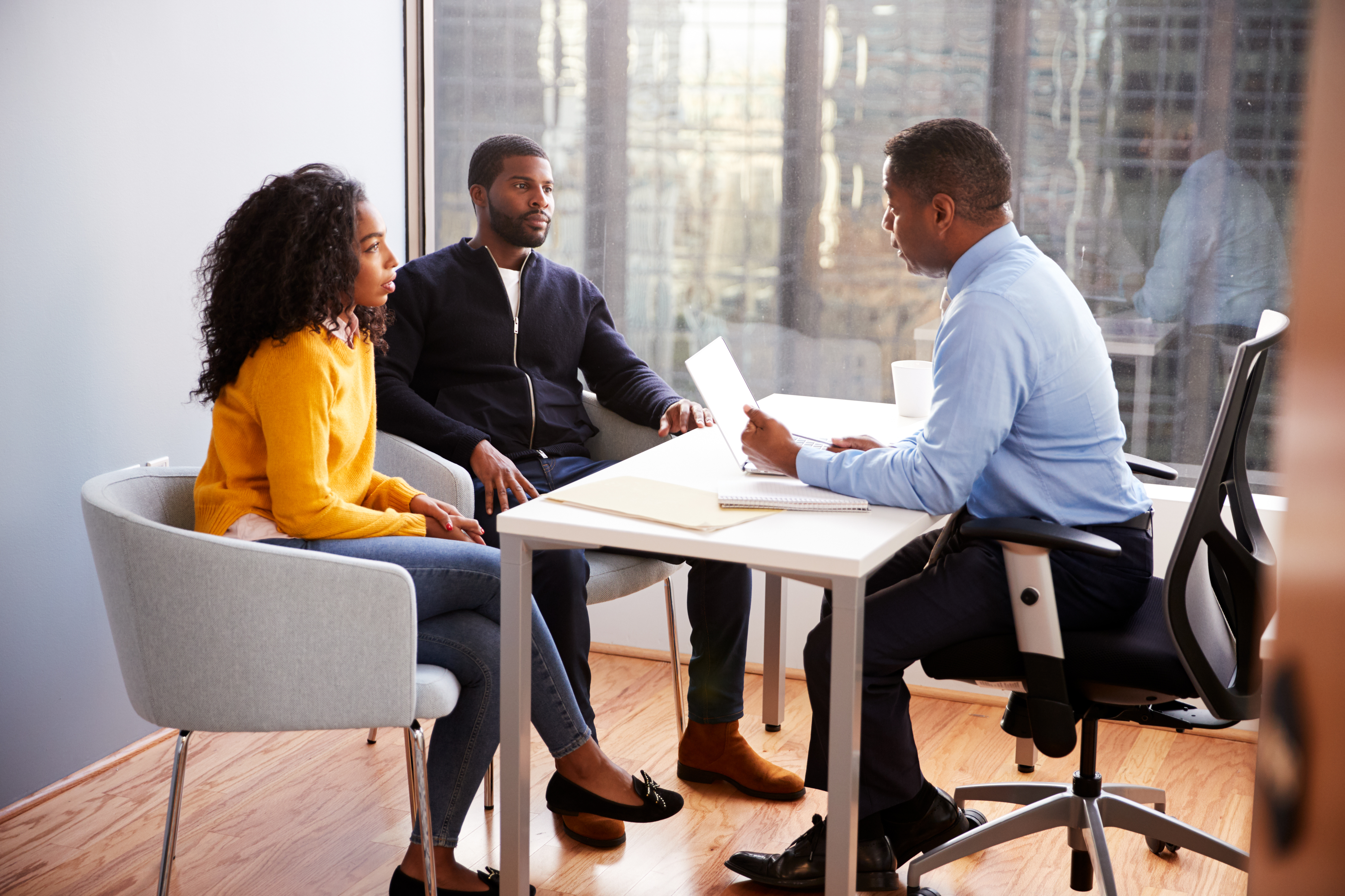 three black persons seated at a table in business attire 