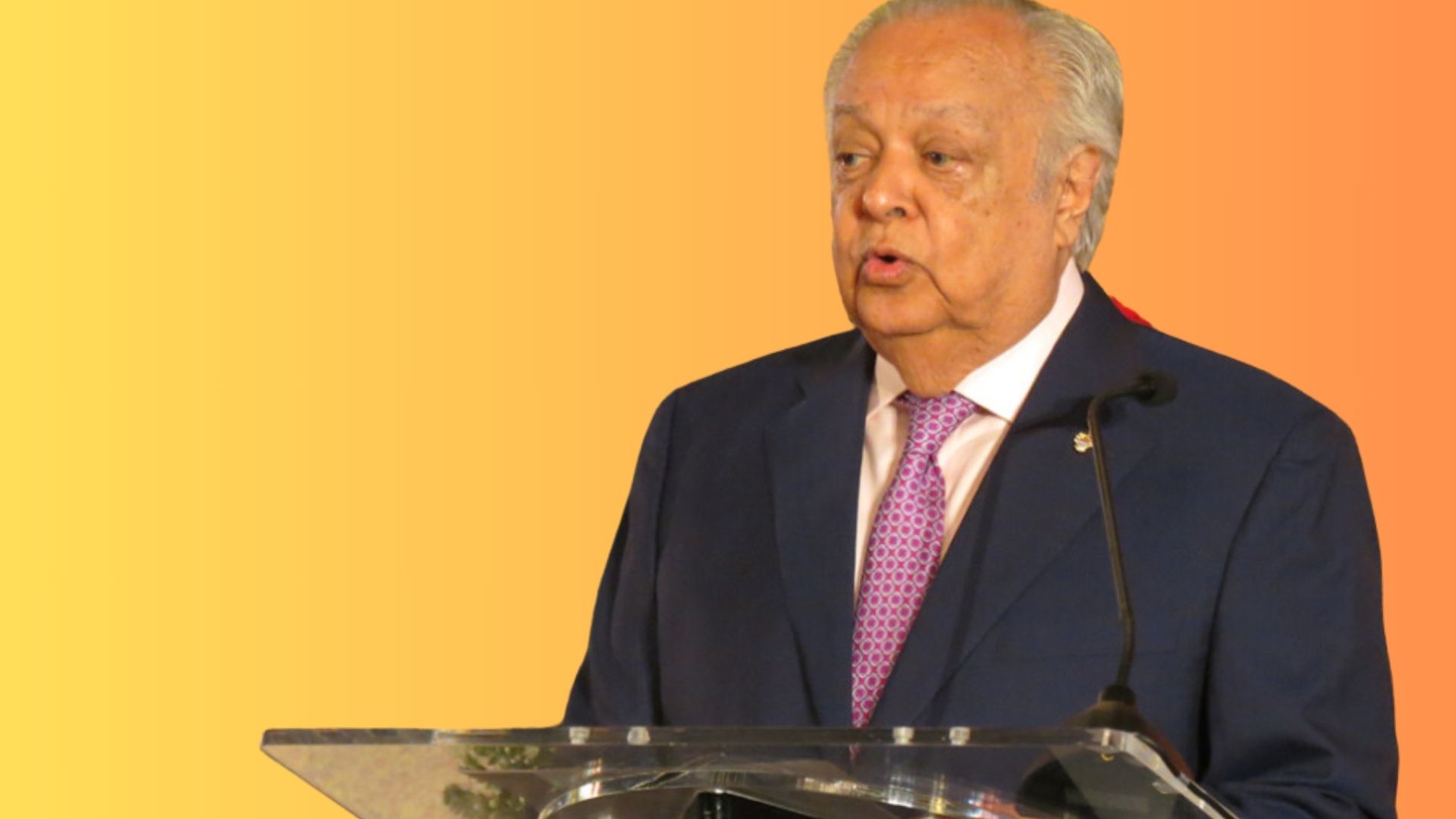 Sir Shridath Ramphal standing in dark suit at lectern