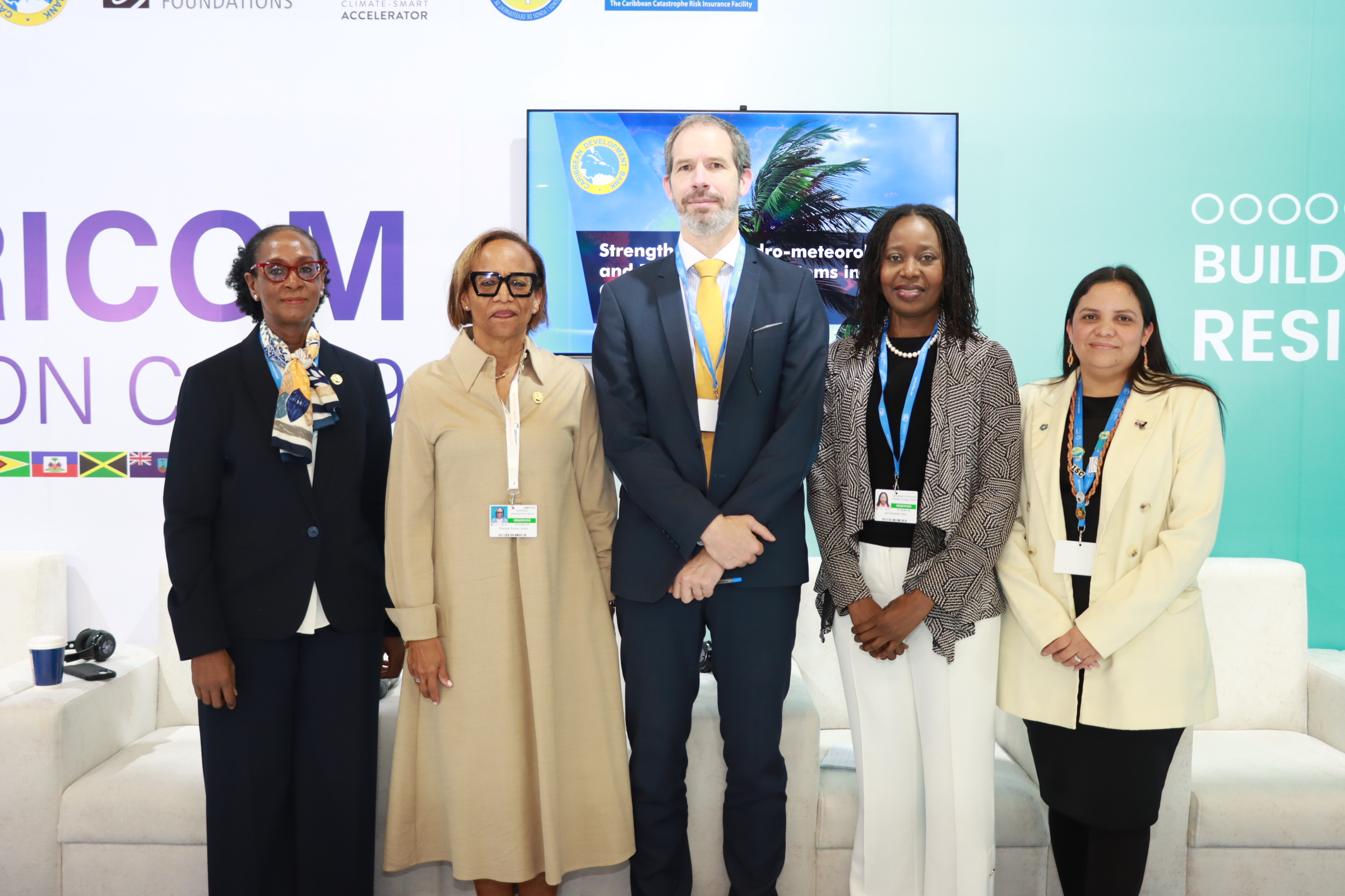 Five individuals, four women and one man, standing next to each other on a platform in front of a COP29 backdrop.