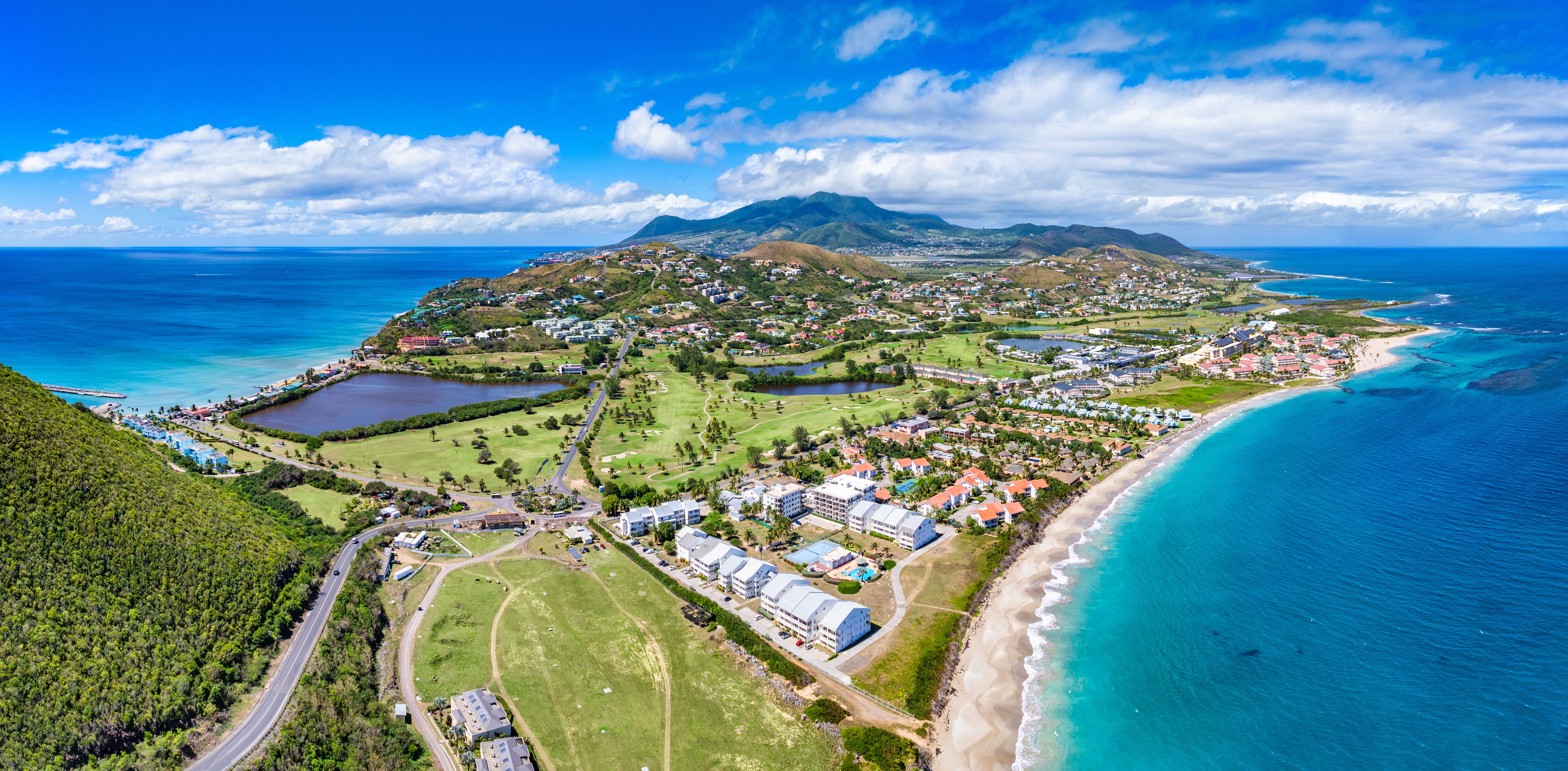 Aerial view of Saint Kitts and Nevis showing blue seas and skies white sands greenery and rooftops at daytime 