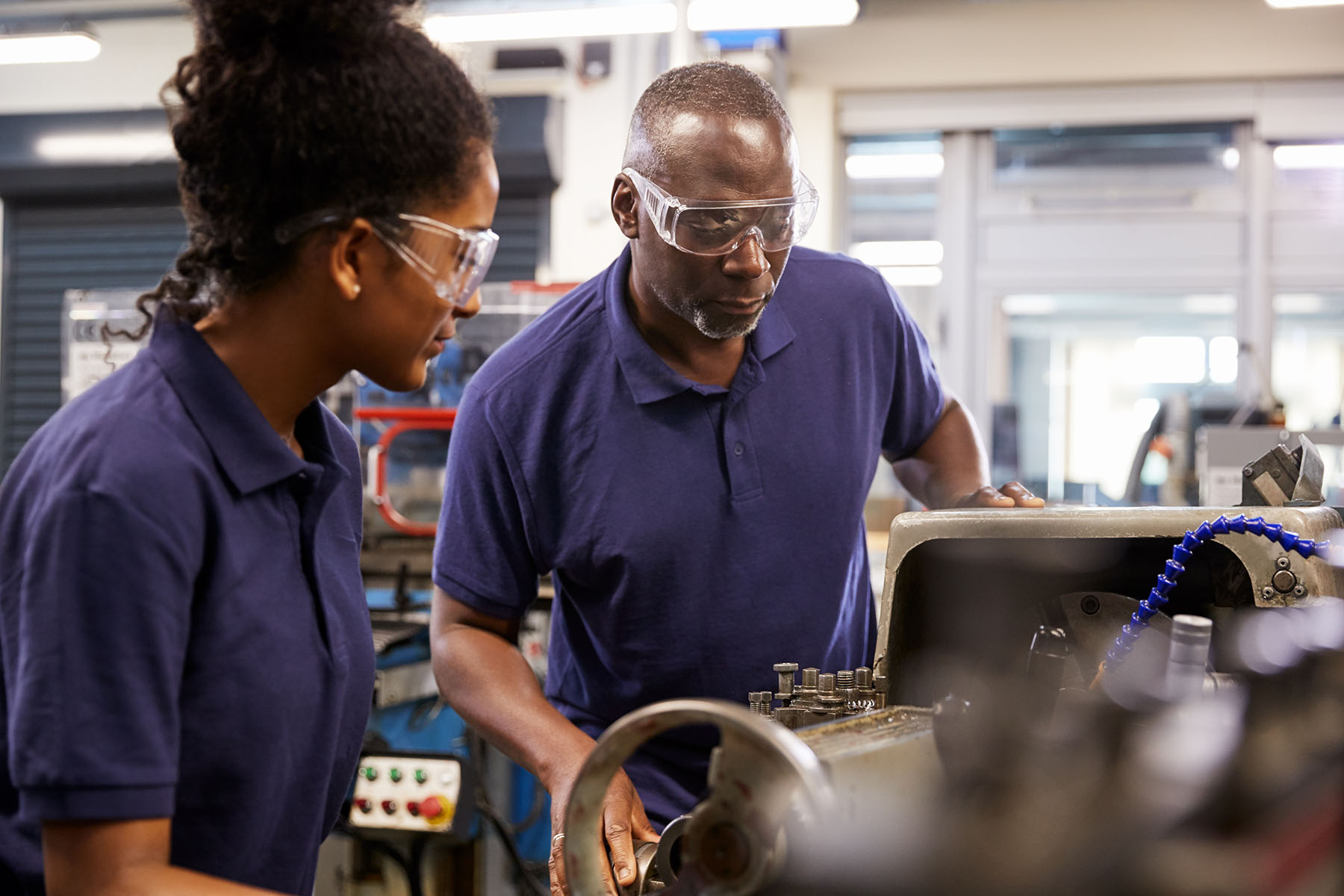 black girl looking on keenly as guys shows her how to use piece of technical equipment