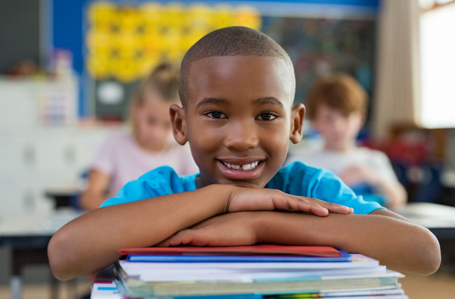 black boy sitting at desk with head on stack of books