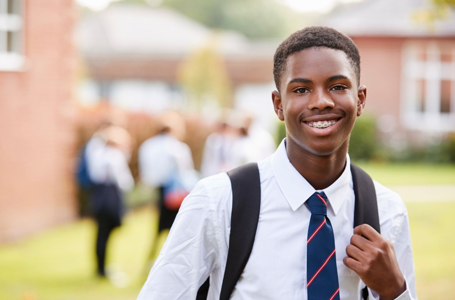 black teenage boy in school uniform looking into camera smiling