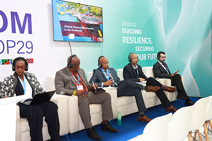 group photo of 1 owman and 4 men dressed in business attire seated in white arm chairs with microphones in hand