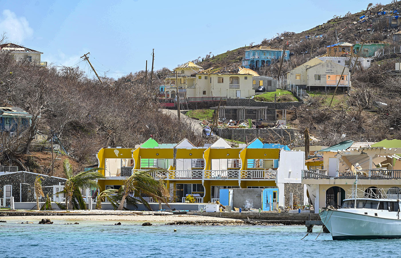 buildings along tropical coastline with roofs missing and other structural damage as caused by high force hurricane winds