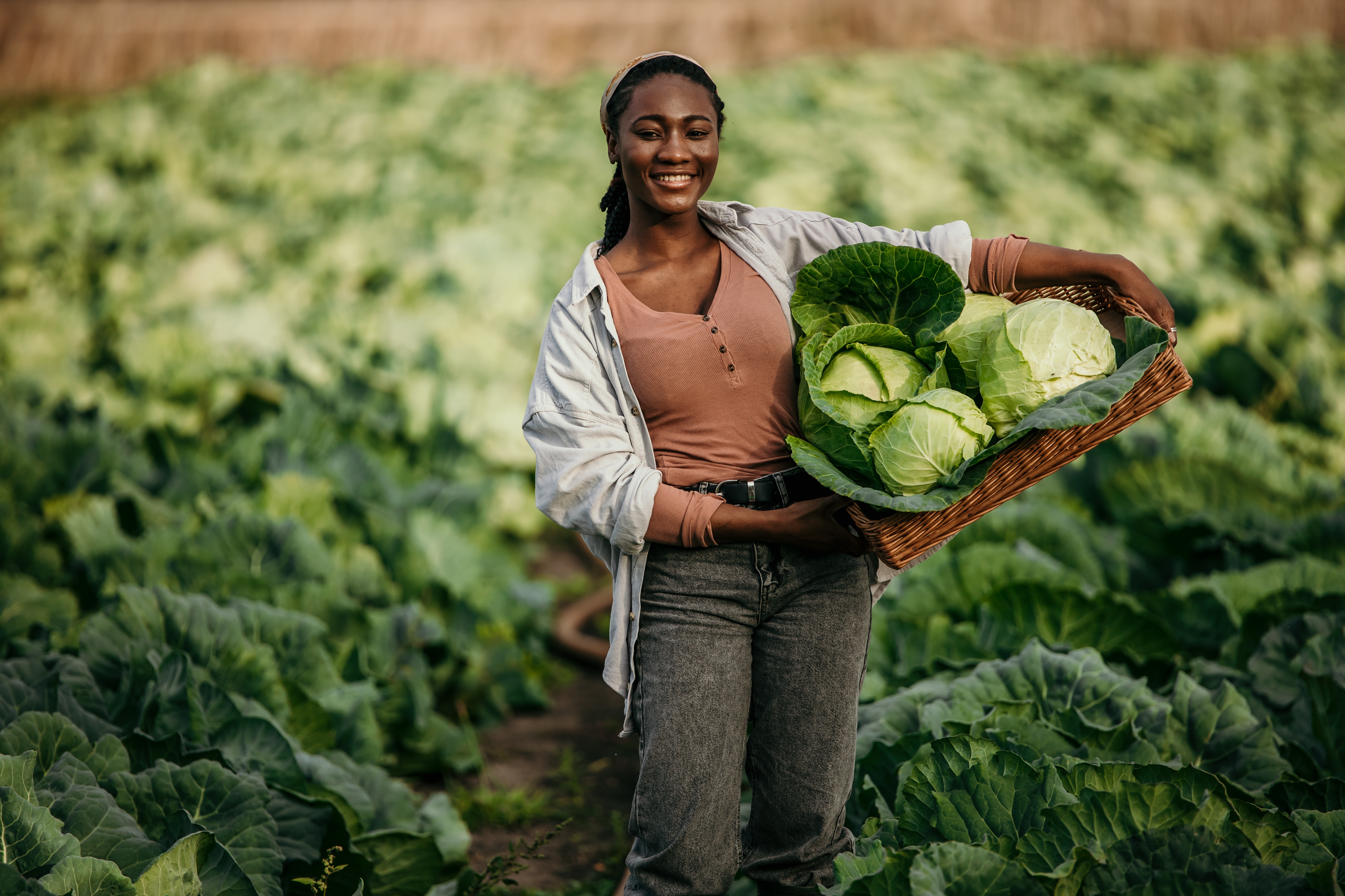 woman in field with basket of produce on hips