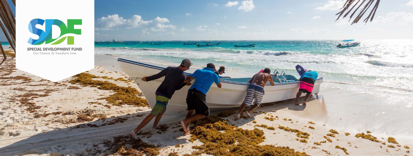 four men on beach pushing small boat into the sea