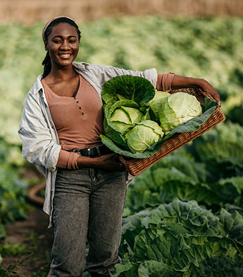 woman in field with basket of goods on hip