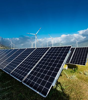 Solar panels farm under the blue sky with wind turbines in the background