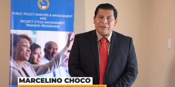 Marcelino Choco wearing a black suit with a white inside shirt and a red tie