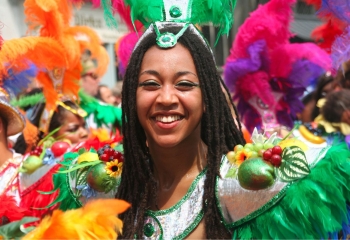 smiling black woman dressed in colourful feathers at a carnival