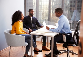 three black persons seated at a table in business attire 