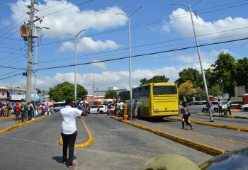 A bus bay featuring buses and taxis and people mulling around 