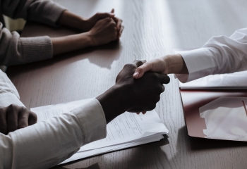 A black sleeved male arm in a white shirt and a white sleeved female arm in a white sleeeved shirt