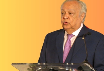 Sir Shridath Ramphal standing in dark suit at lectern