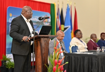 Black man standing at a lectern in a suit delivering a speech 