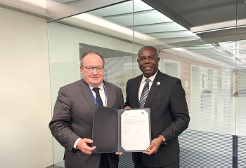 two gentlemen in suits standing holding a signed document