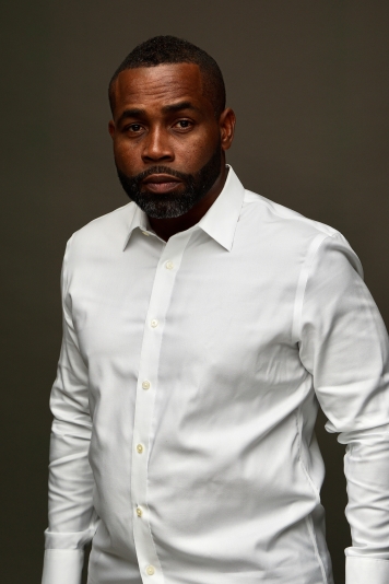 Black man standing in white long sleeved short 