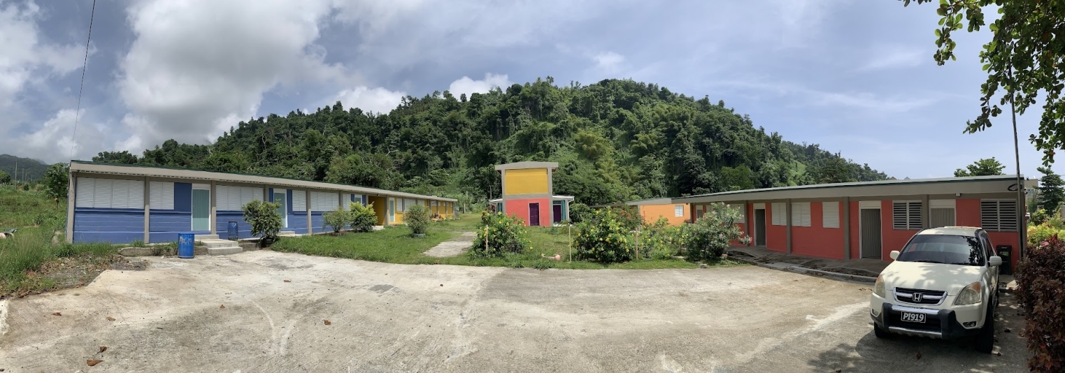 three brightly coloured primary school structures in a tropical environment