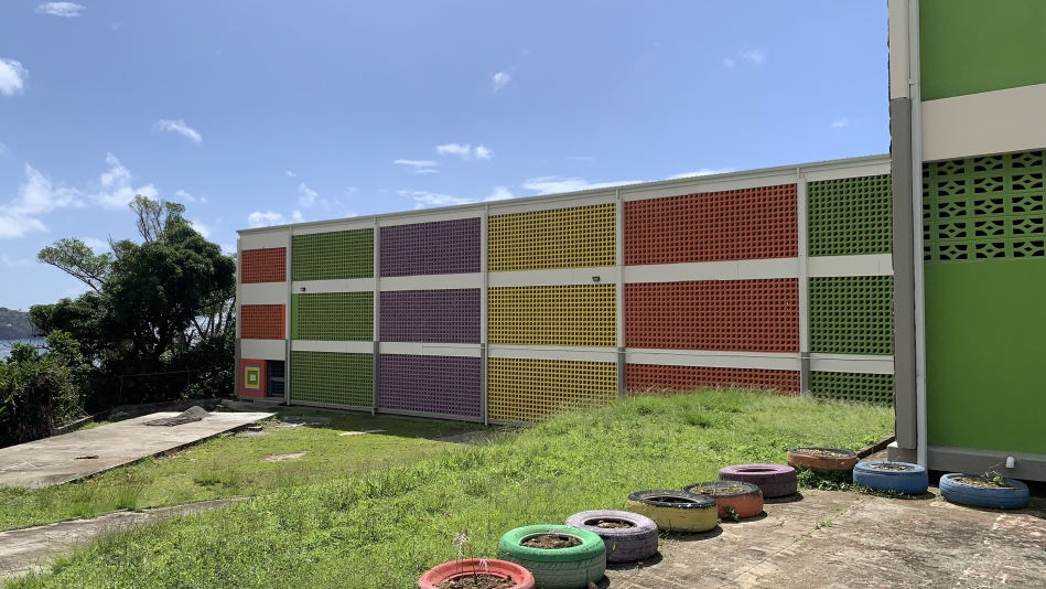 Multi storey multi coloured two level primary school with vibrant green vegetation and bright blue sky