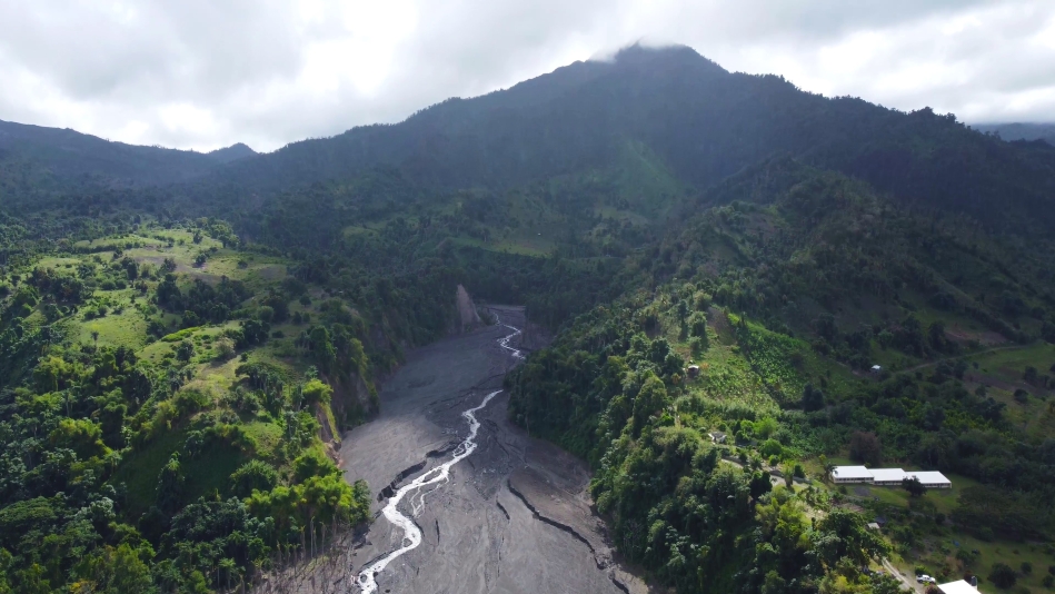 lush green landscape with aerial view of black filled volcano crater 