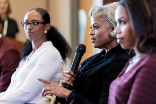 Mature black businesswoman gestures while answering a question during a discussion